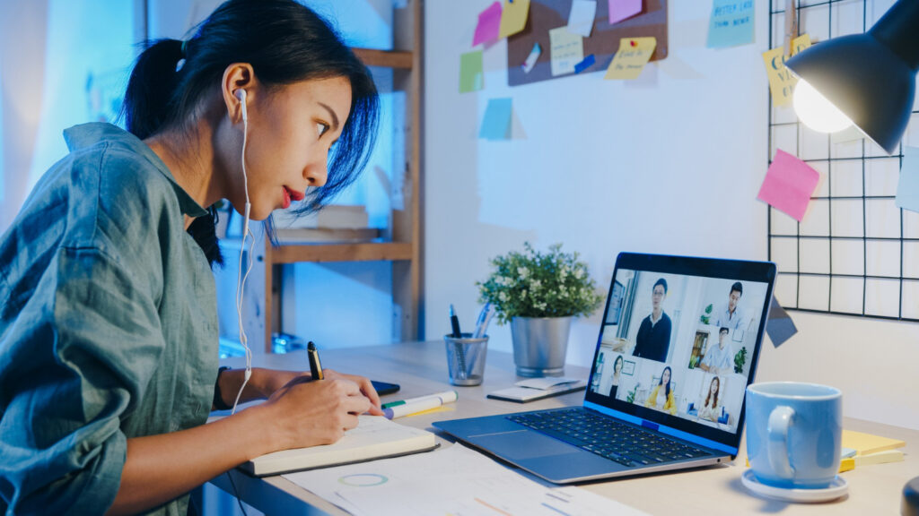 Asia businesswoman using laptop talk to colleagues about plan in video call meeting at living room.